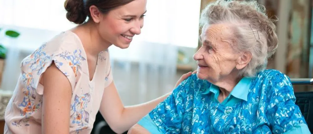 Foto de una señora mayor hablando con una mujer que le sonrie