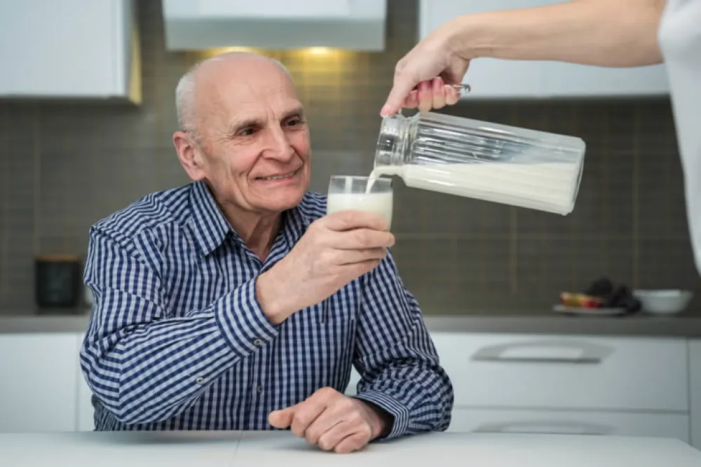 Persona mayor a la que se le está sirviendo un vaso de leche