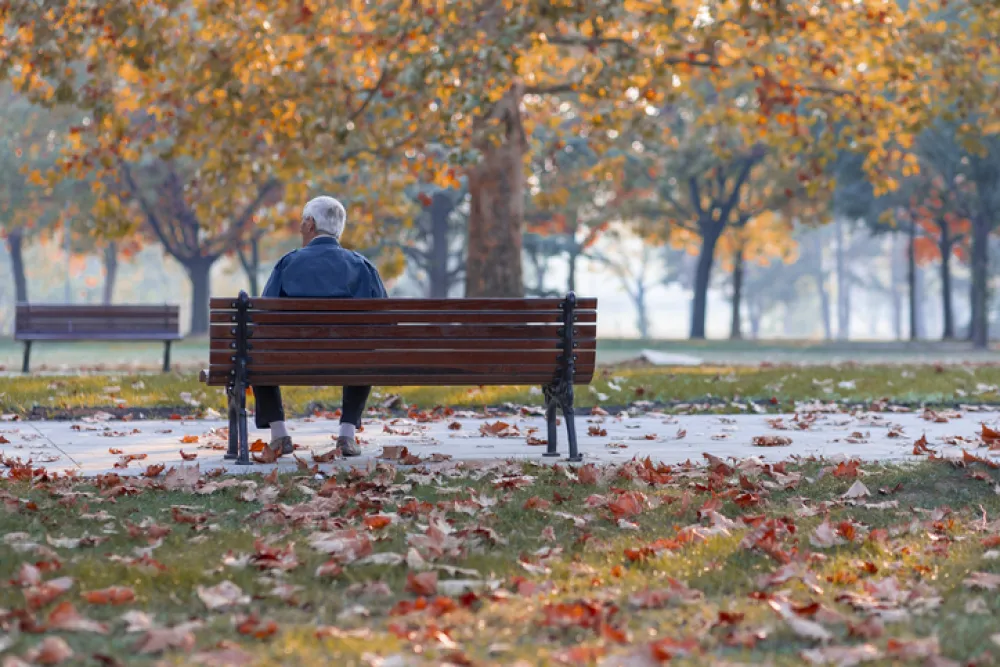 Foto de una persona mayor sentada en un banco en un parque