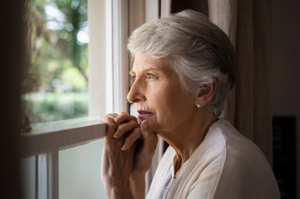 Foto de una señora mayor mirando por la ventana