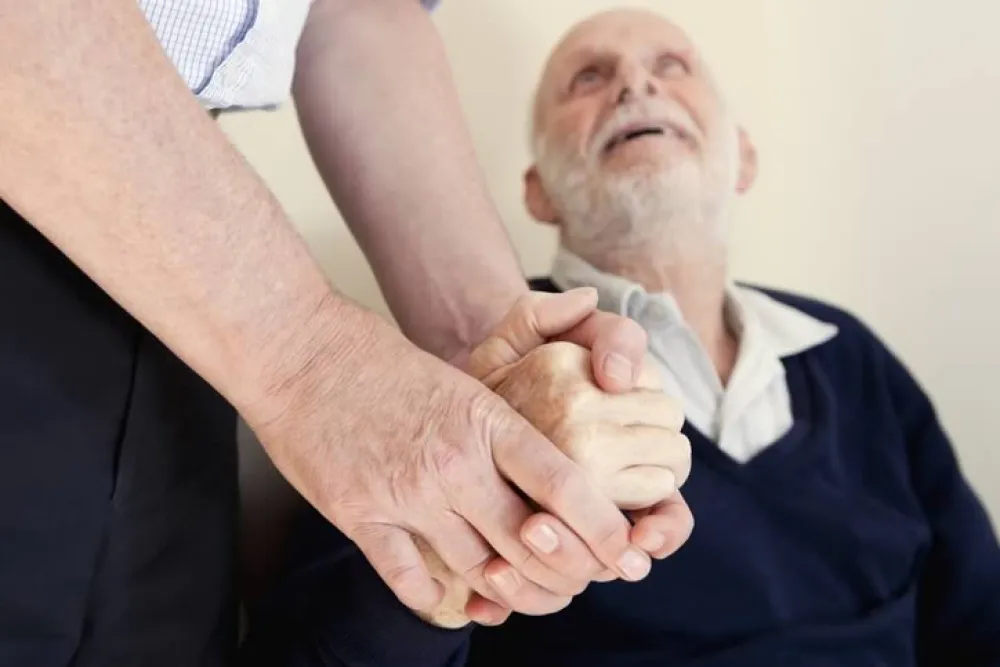 Persona sujetando las manos a un hombre mayor