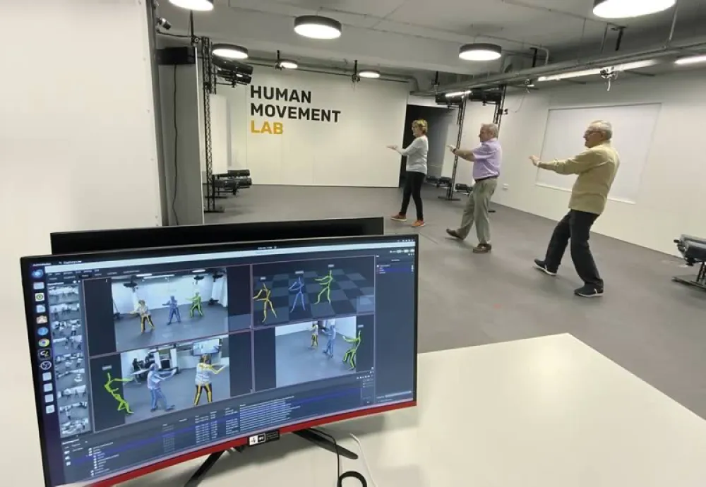Monitorización del movimiento de tres personas mayores en un entorno de pruebas. En la pared el texto Human Movement Lab.